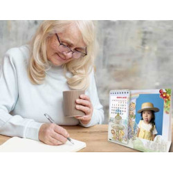 Mujer escribiendo y tomando café sobre una mesa en la que se ve el calendario de mesa con ilustraciones de Madrid.